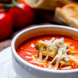 portrait shooting tomato soup with crackers and cheese tomatoes and bread on the table